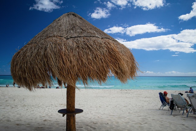 a straw umbrella sitting on top of a sandy beach