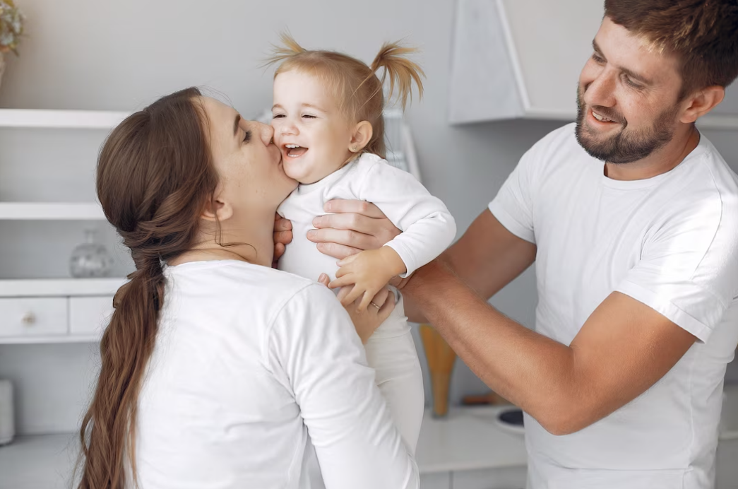 mother and father with a little daughter having fun at home