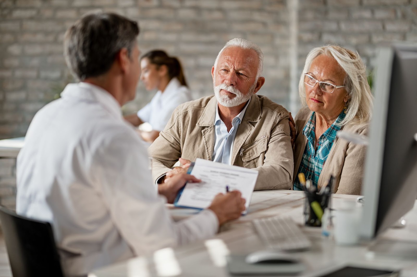 Alt: Senior couple consulting with healthcare worker about their insurance policy