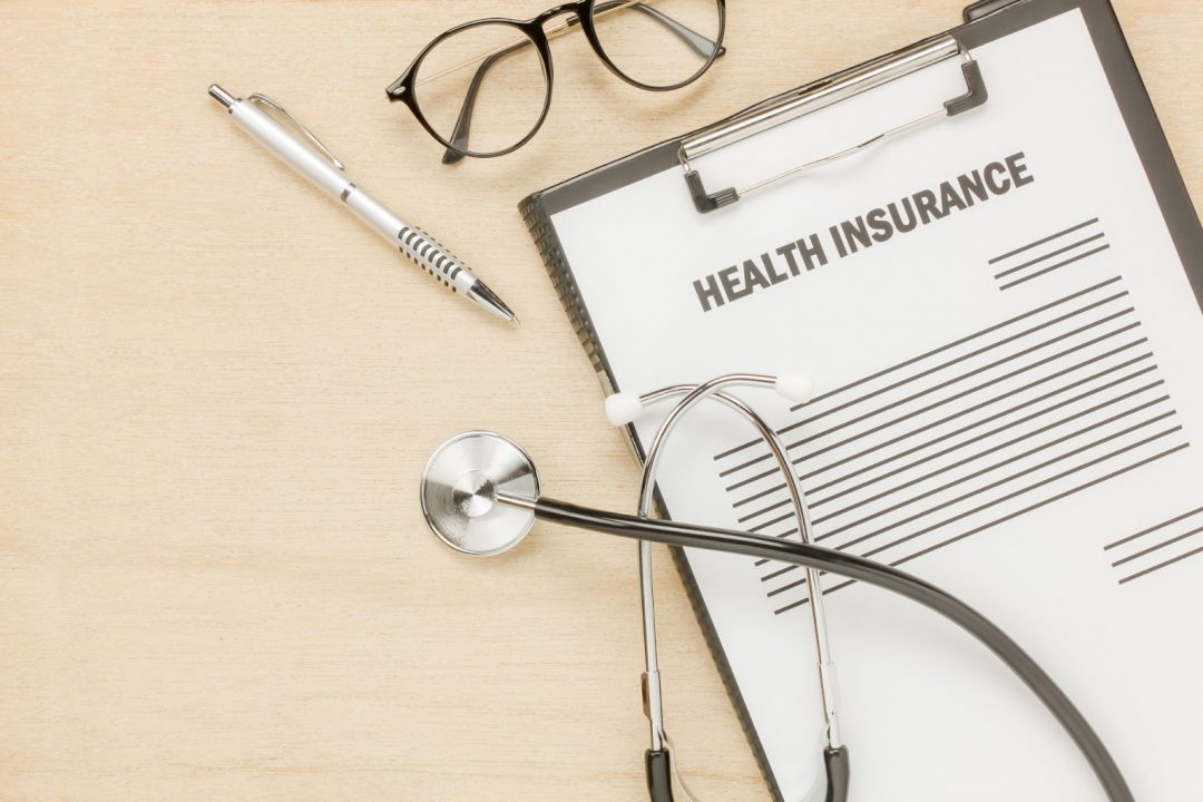 Top view of health insurance form and eyeglasses with stethoscope