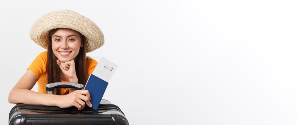 A smiling woman in a hat with a passport and boarding pass leans on a suitcase.
