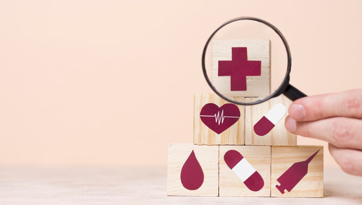 Wooden blocks with health symbols being examined through a magnifying glass.