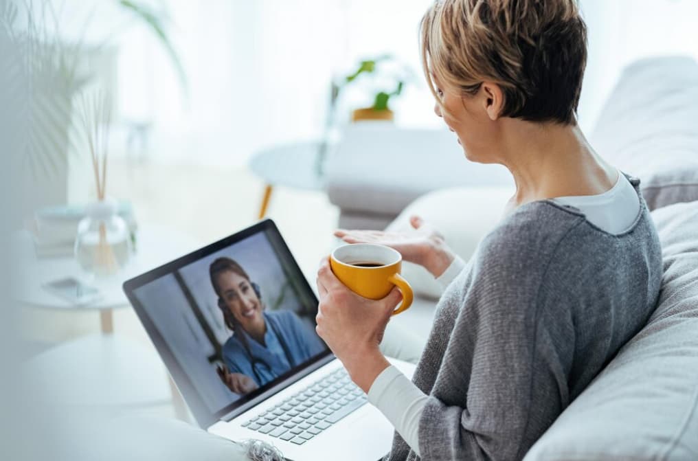 A woman enjoys a video call while holding a yellow mug.