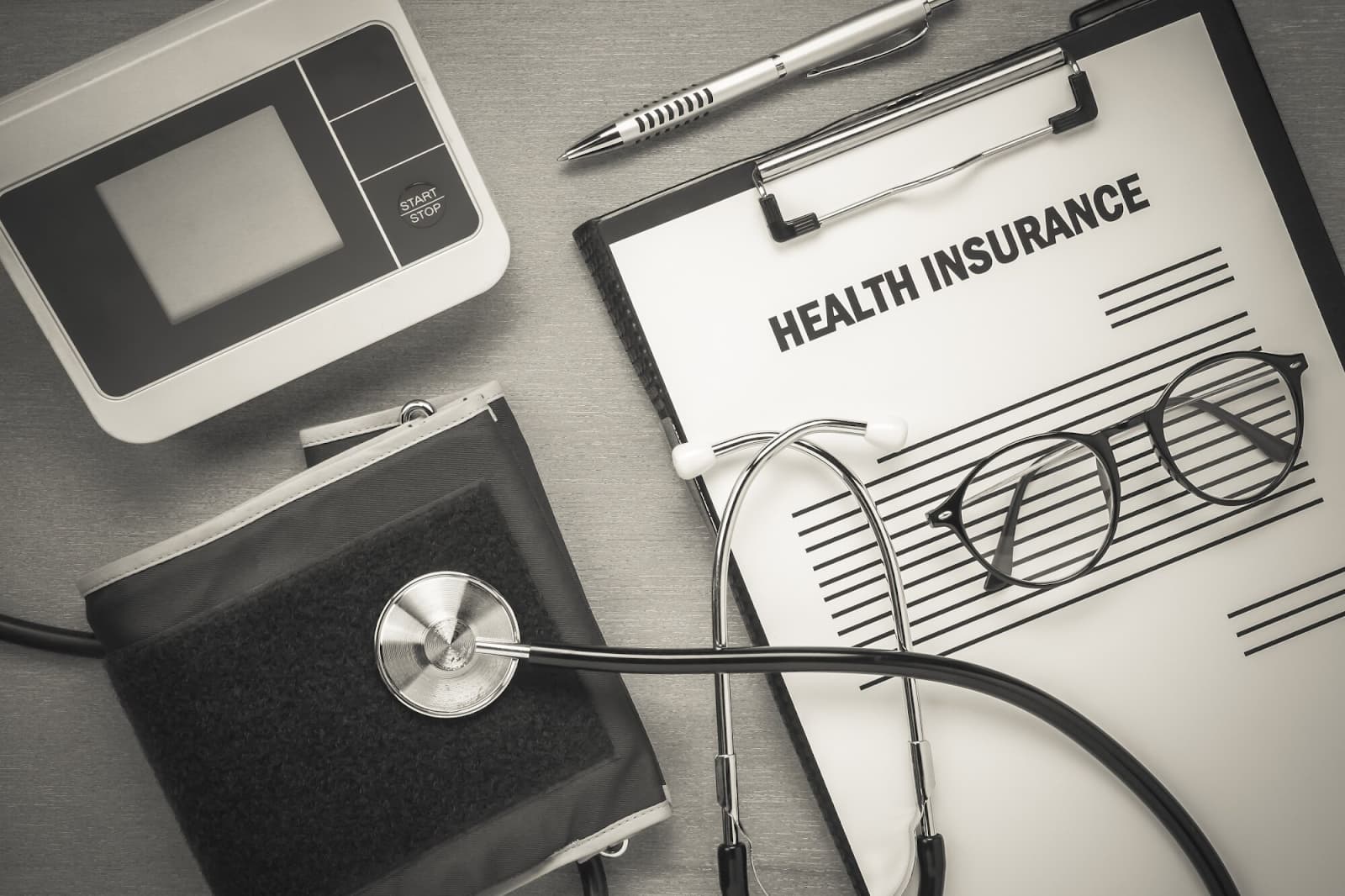 Top view of health insurance and heart rate monitor with stethoscope on wooden background